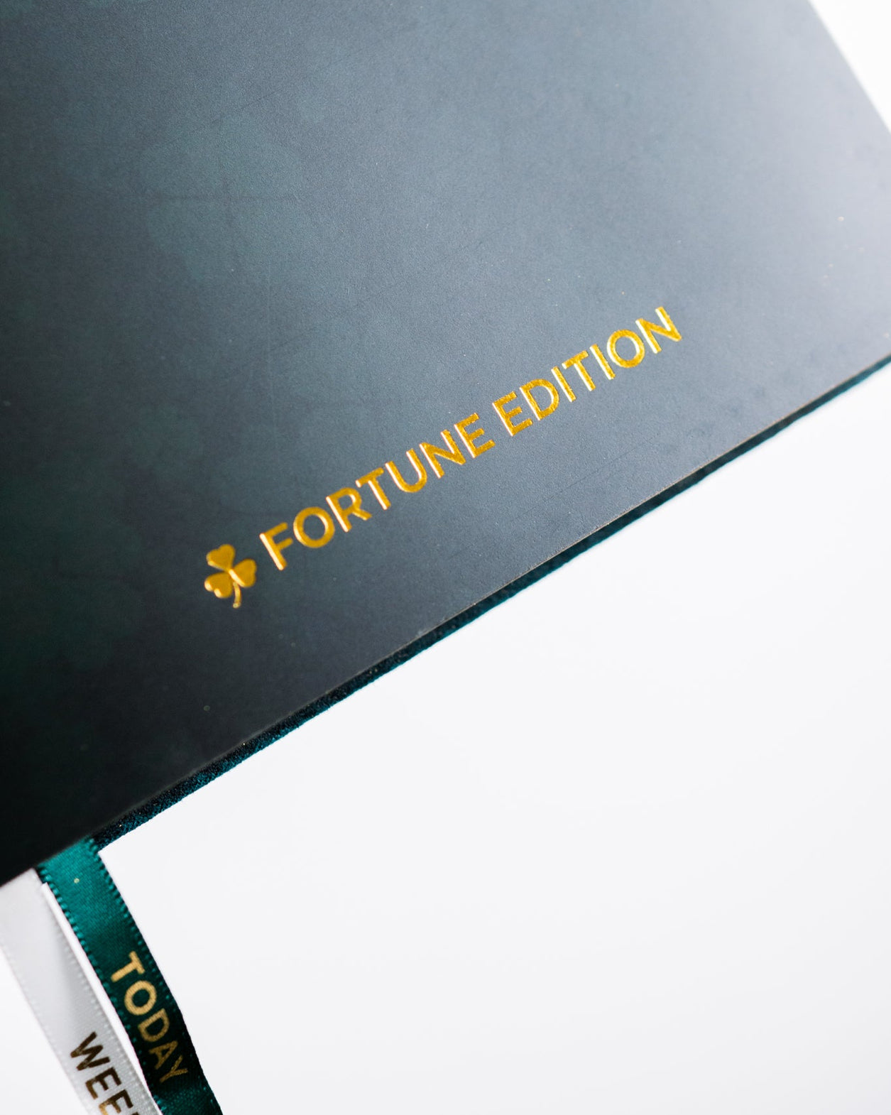 Dark green notebook with 'Fortune Edition' text and clover symbol on a white background